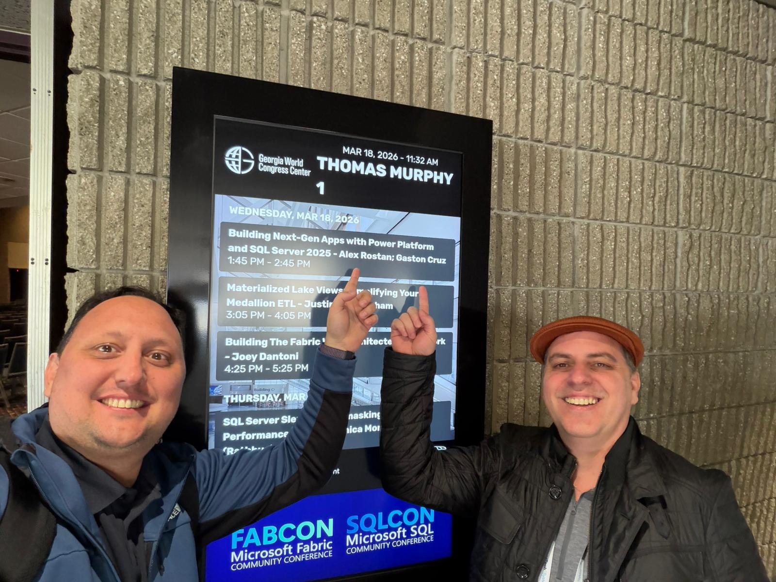 Alex Rostan and Gaston Cruz pointing at their FabCon session on the schedule board - Wednesday March 18