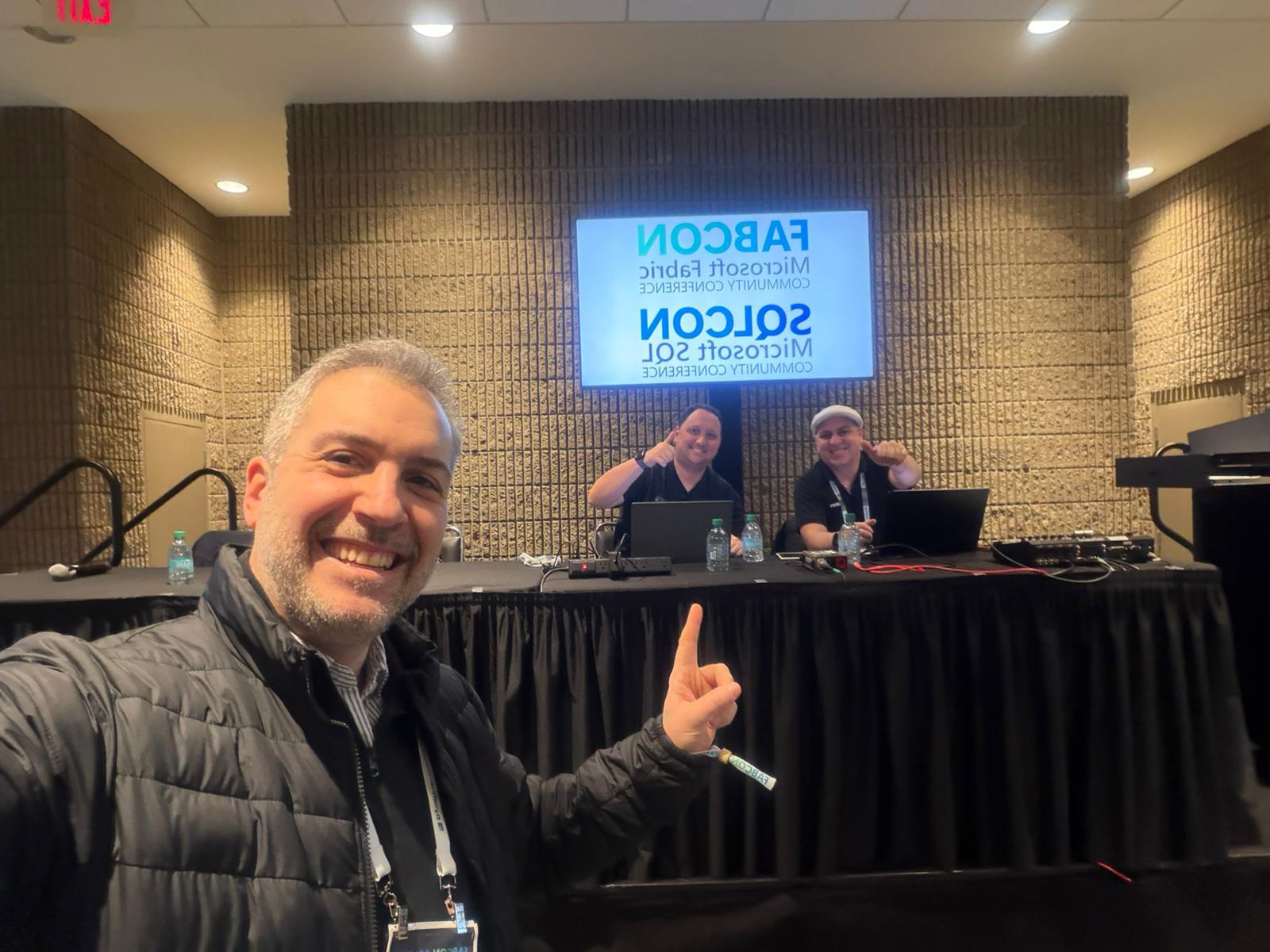Gaston Cruz at the FabCon speaker table with Alex Rostan and the FabCon/SQLCon branding on screen